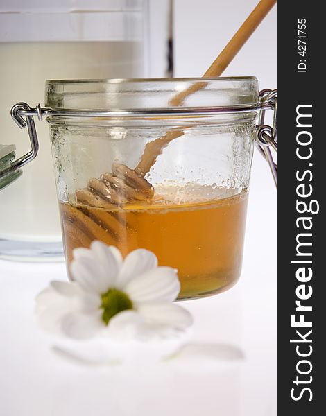 Glass honey with sticks and flower