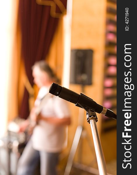 Microphone on tripod with guitarist on background