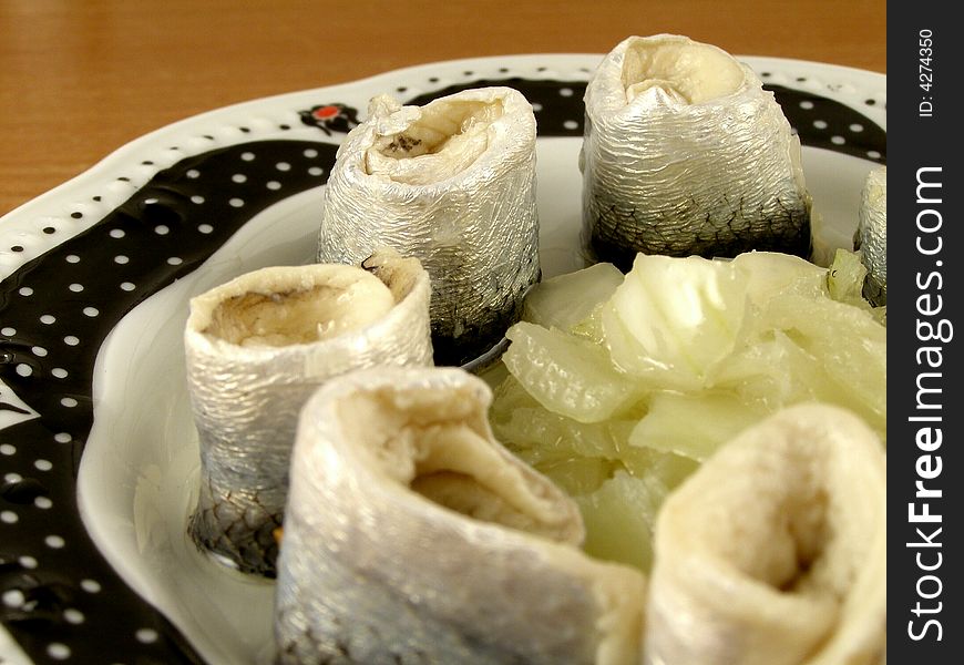 A close up of rolled herring in oil with onion. A close up of rolled herring in oil with onion.