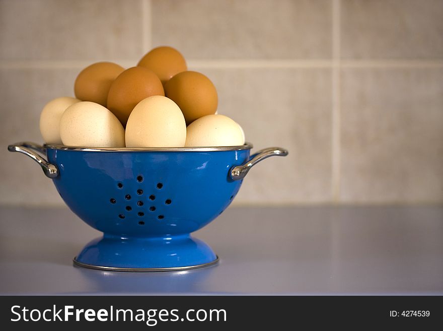 Blue metal colander filled with a dozen eggs. Blue metal colander filled with a dozen eggs