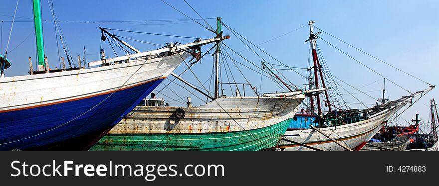 Indonesia, Jakarta: boats at Sunda Kelapa an ancient sea port; one of the most famous ports for the construction of the traditional wood boats; blue sky and colorful big wood boats. Indonesia, Jakarta: boats at Sunda Kelapa an ancient sea port; one of the most famous ports for the construction of the traditional wood boats; blue sky and colorful big wood boats