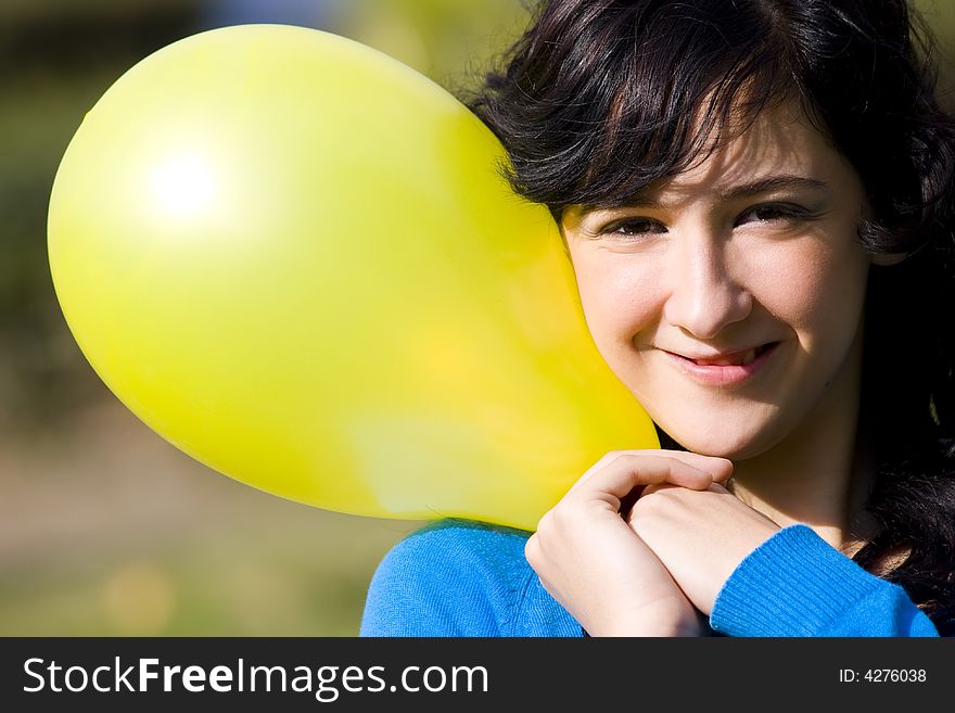 Cute girl with yellow colored balloon in the park