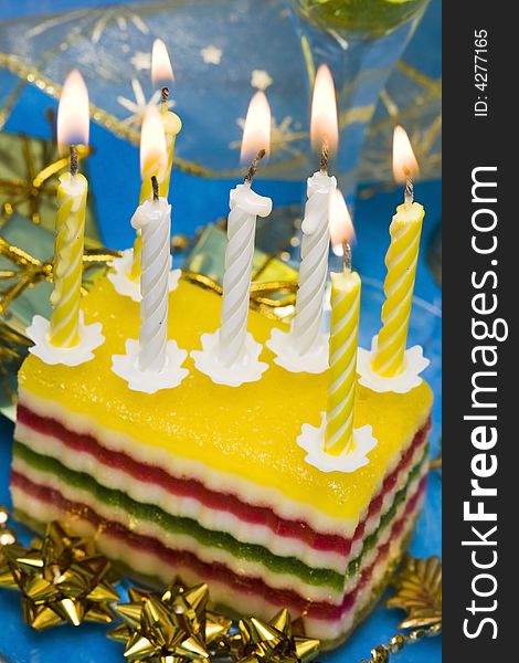 Celebratory table (cake and candles, two glasses with champagne, gift boxes) on blue