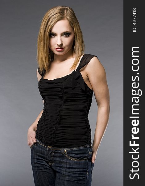 Beautiful blonde model wearing black shirt posing on grey backgound. Beautiful blonde model wearing black shirt posing on grey backgound