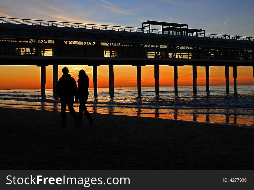 Pair walking on the beach watching sunset on Dutch seaside, Scheveningen. Pair walking on the beach watching sunset on Dutch seaside, Scheveningen