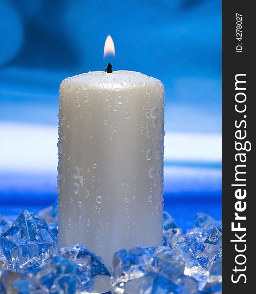 Candle with ice on blue background