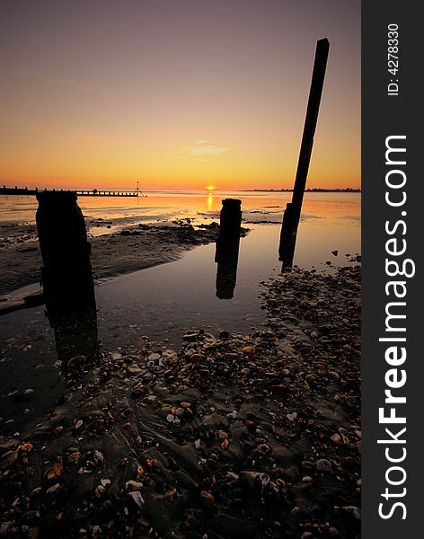Sun setting on a West Wittering beach with groyns in the foreground. Sun setting on a West Wittering beach with groyns in the foreground