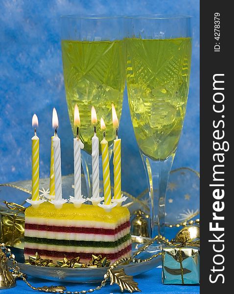 Celebratory table (cake and candles, two glasses with champagne, gift boxes) on blue
