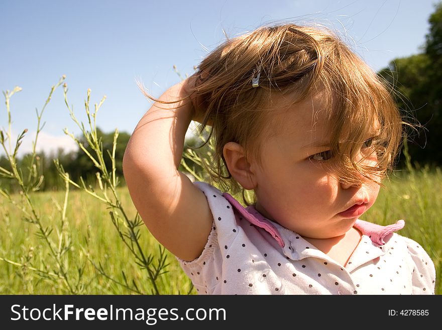A little girl trying to hold her hair back from the wind. A little girl trying to hold her hair back from the wind