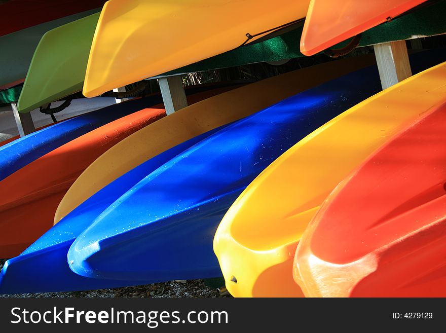 Brightly colored kayaks for rent stacked in racks. Brightly colored kayaks for rent stacked in racks