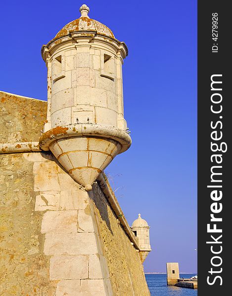 Portugal, area of Algarve, Lagos: typical architecture. Blue sky and yellow stone fortress; detail of one tower of control. Portugal, area of Algarve, Lagos: typical architecture. Blue sky and yellow stone fortress; detail of one tower of control