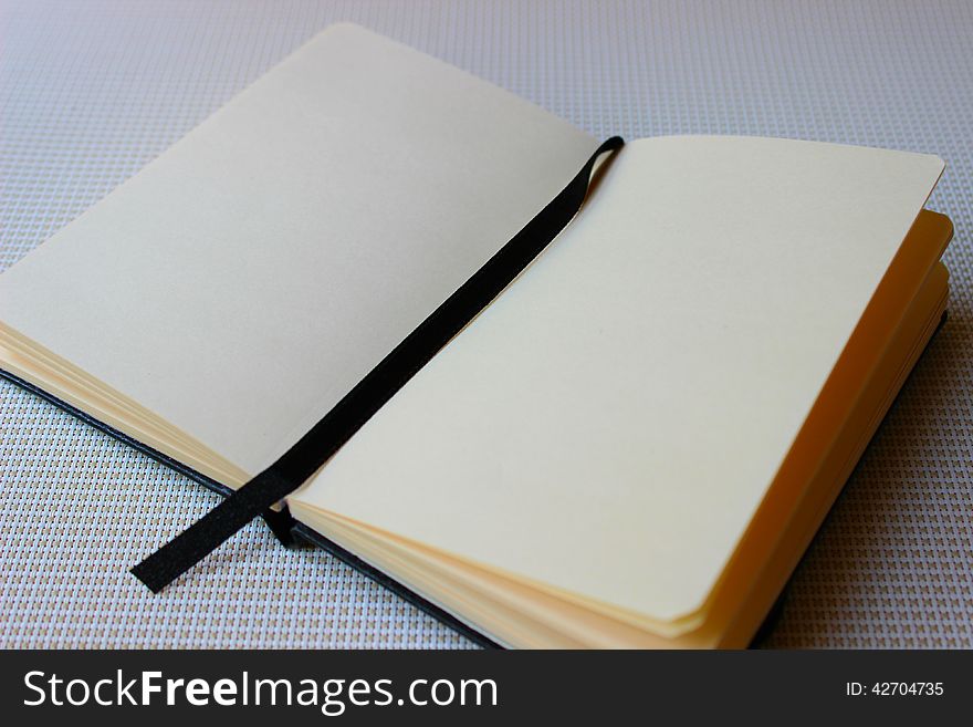 An open black book with white yellowish paper.
