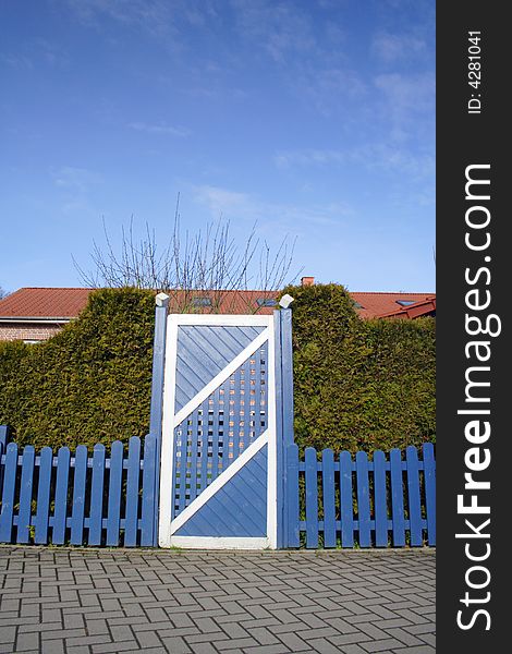 A blue and white gate with blue fance and blue sky