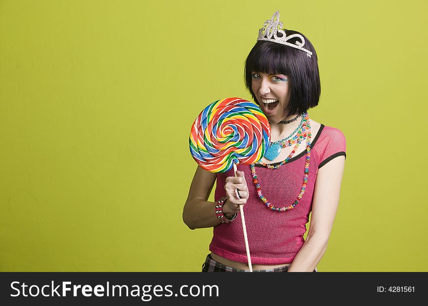 Pretty young woman takes a bite from a large lollipop. Pretty young woman takes a bite from a large lollipop