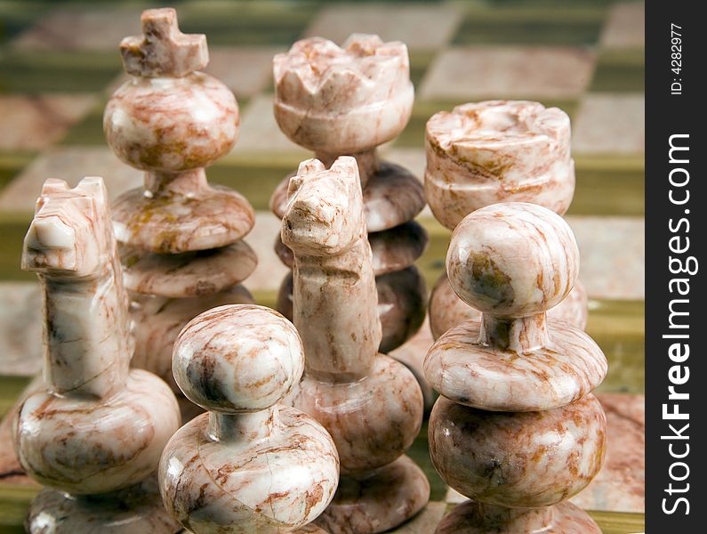 Group of stone chess pieces on stone chessboard. Group of stone chess pieces on stone chessboard