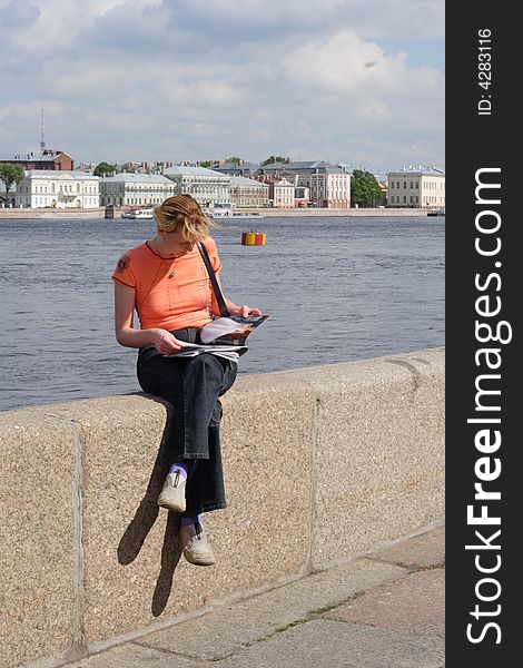 Girl reading magazine on canal border in Saint Petersburg