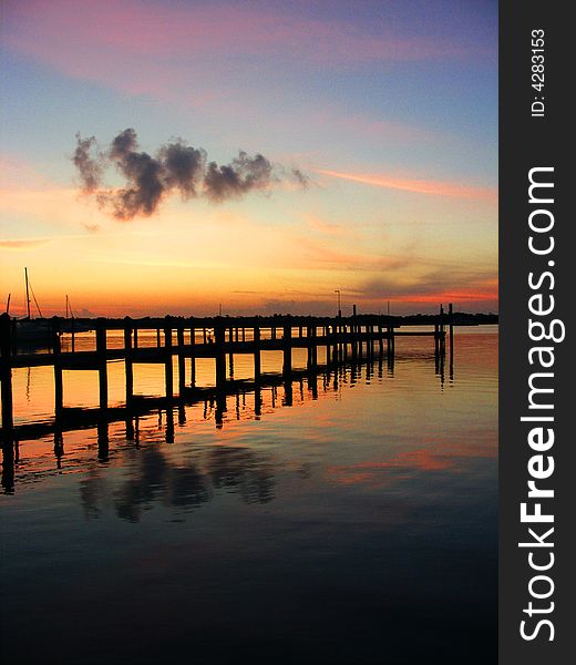Sunset over pier in florida keys containing dark cloud. Sunset over pier in florida keys containing dark cloud