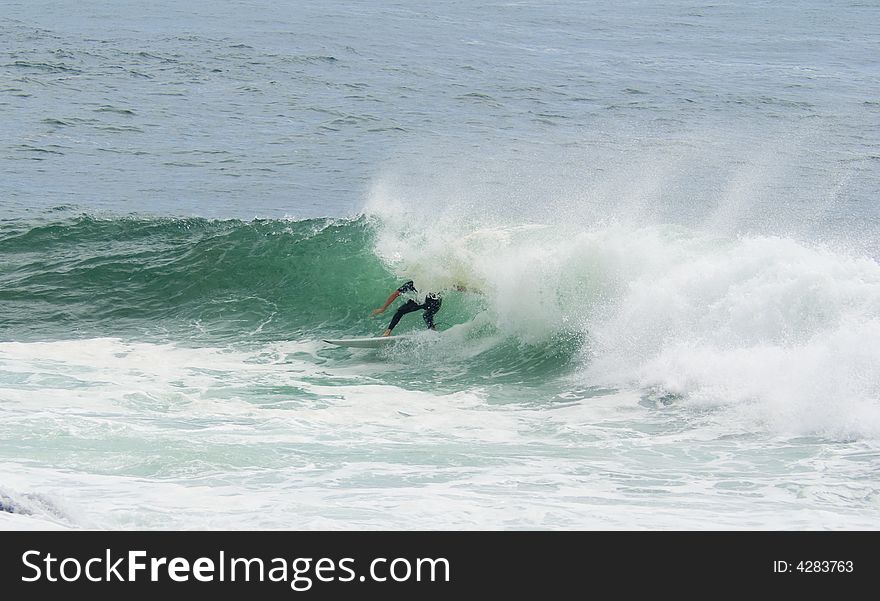 A surfer surfing out of a big wave about to dump him. A surfer surfing out of a big wave about to dump him