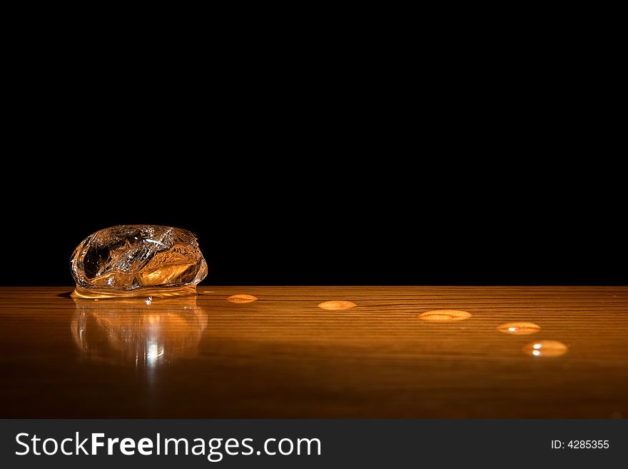 Ice cube and drops of water in dark background. Nice wooden table. Ice cube and drops of water in dark background. Nice wooden table.