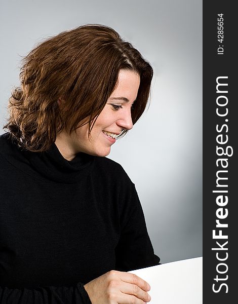 Smiling woman holding a blank white card looking to the right. Card is only partly visible. Smiling woman holding a blank white card looking to the right. Card is only partly visible.