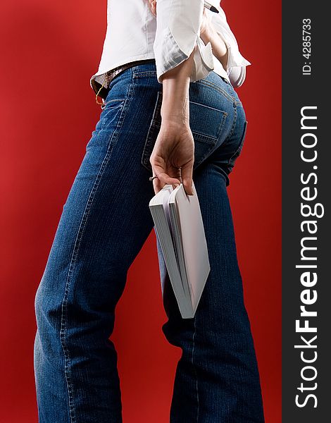 Woman in Jeans with book on outstretched arm. Perspective from behind and low. Without upper body. Variation. Woman in Jeans with book on outstretched arm. Perspective from behind and low. Without upper body. Variation.