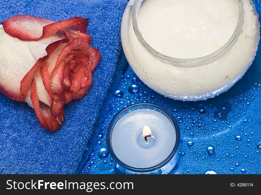 Cream, candle with rose on blue background