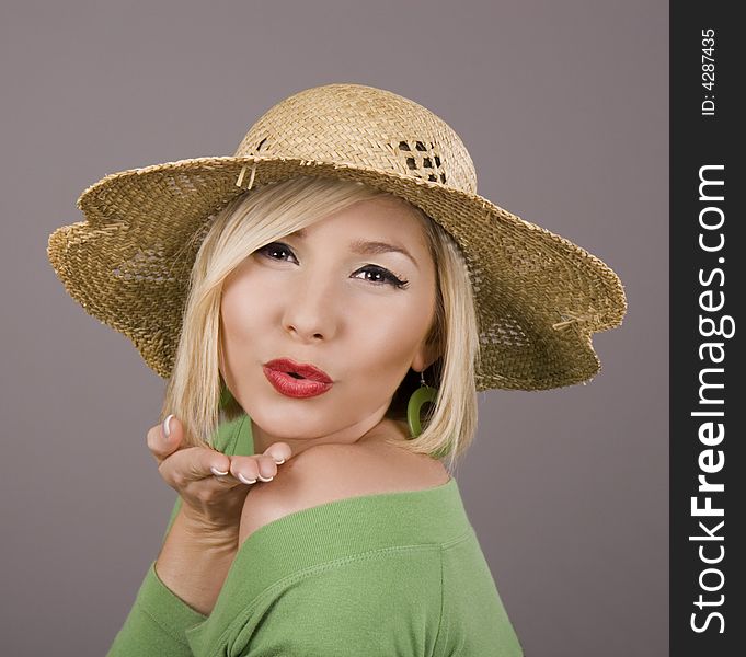 A blonde model in a green blouse and a straw hat blowing a kiss at the camera. A blonde model in a green blouse and a straw hat blowing a kiss at the camera