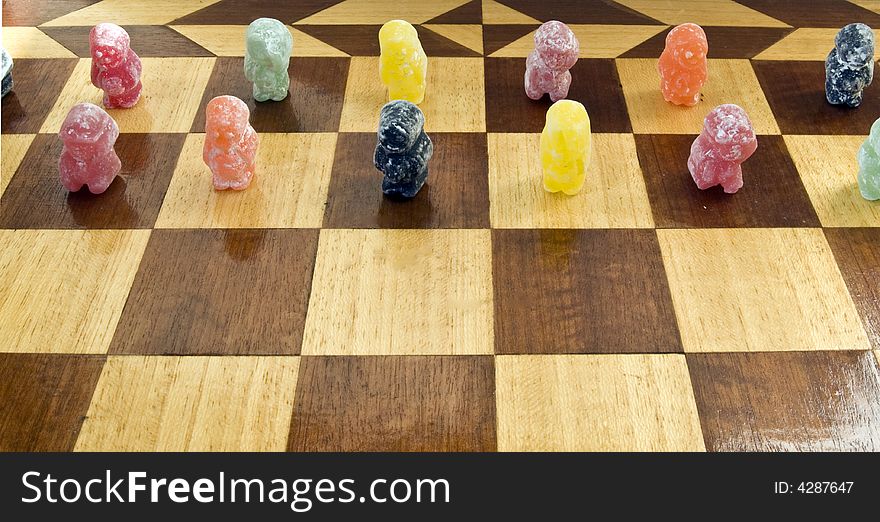 Various coloured jelly-babies pictured on a chess board. Various coloured jelly-babies pictured on a chess board