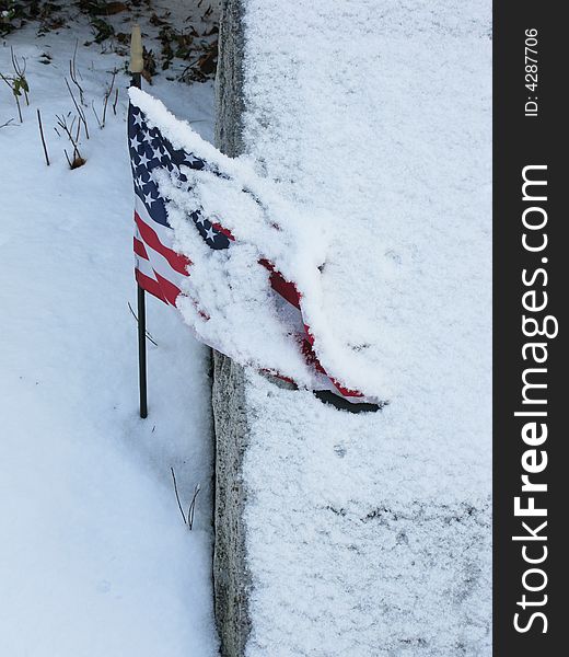 US flag and tombston were covered by snow