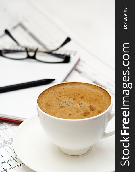 Cup of coffee with notepad and glasses.