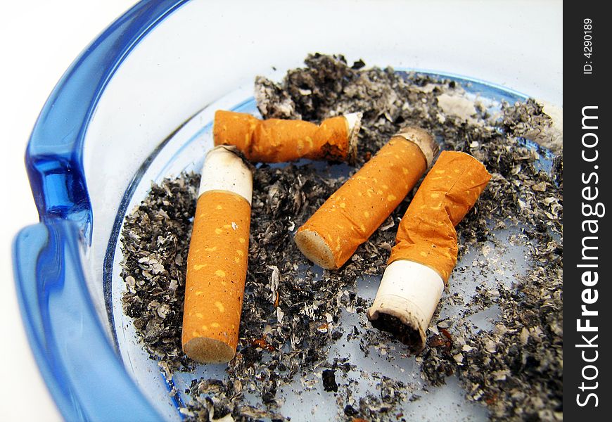 Blue glass ashtray with cigarette on white