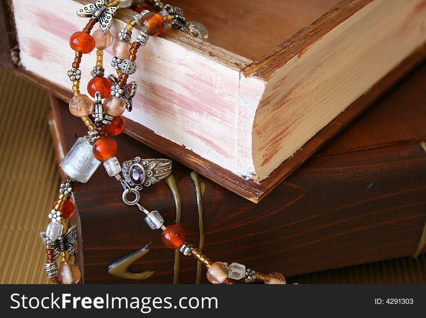 Orange Jewellery hanging from an open wooden jewellery box and a purple stone ring. Orange Jewellery hanging from an open wooden jewellery box and a purple stone ring