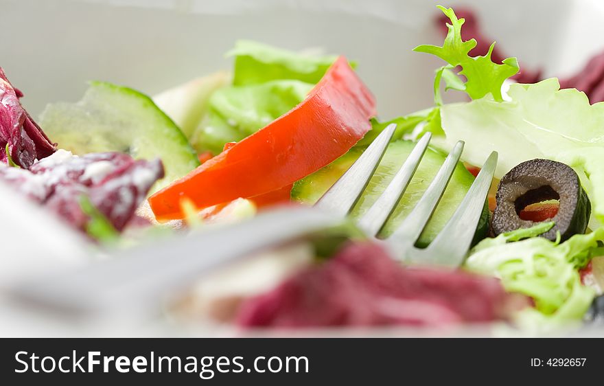 Closeup on a fork in a bowl of salad. Closeup on a fork in a bowl of salad