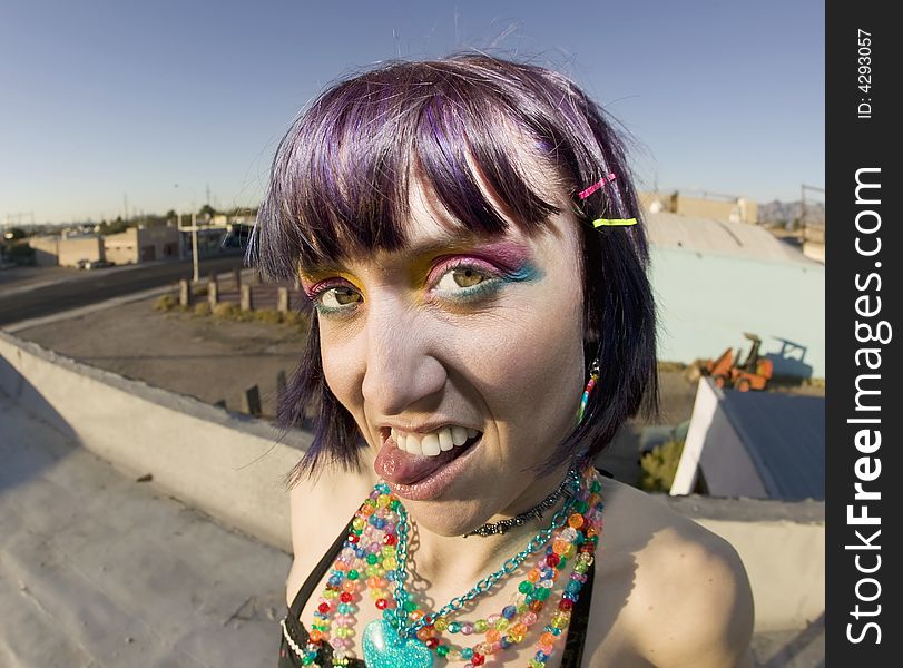 Fisheye shot of young woman sticking out her tongue on a roof. Fisheye shot of young woman sticking out her tongue on a roof