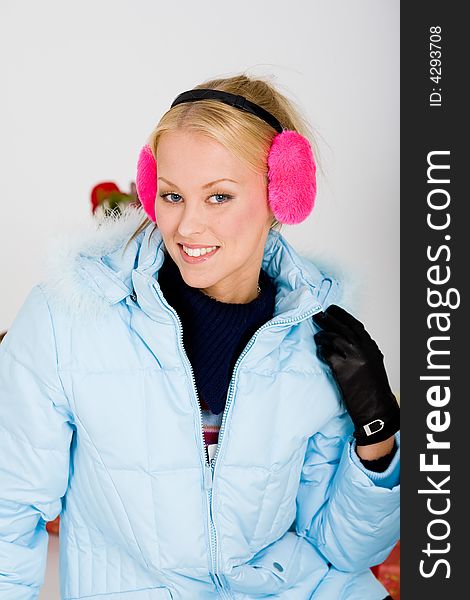 Young blond woman in aqua hooded coat feeling cold and happy. Young blond woman in aqua hooded coat feeling cold and happy