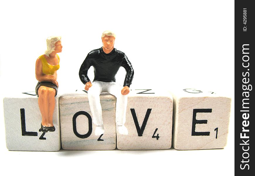 Two figurines sitting on the word love