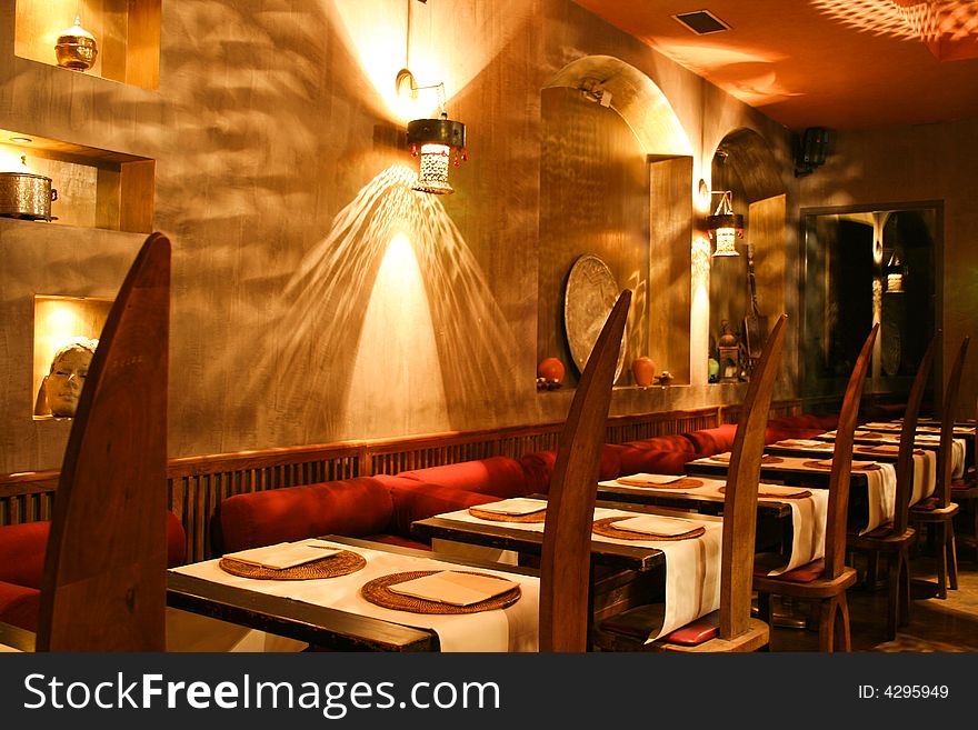 Exotic, moody lighting in a restaurant with pointed, high-backed chairs. Exotic, moody lighting in a restaurant with pointed, high-backed chairs