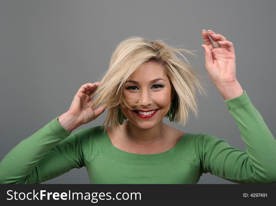 A blonde fashion model in green blouse messing up her hair. A blonde fashion model in green blouse messing up her hair