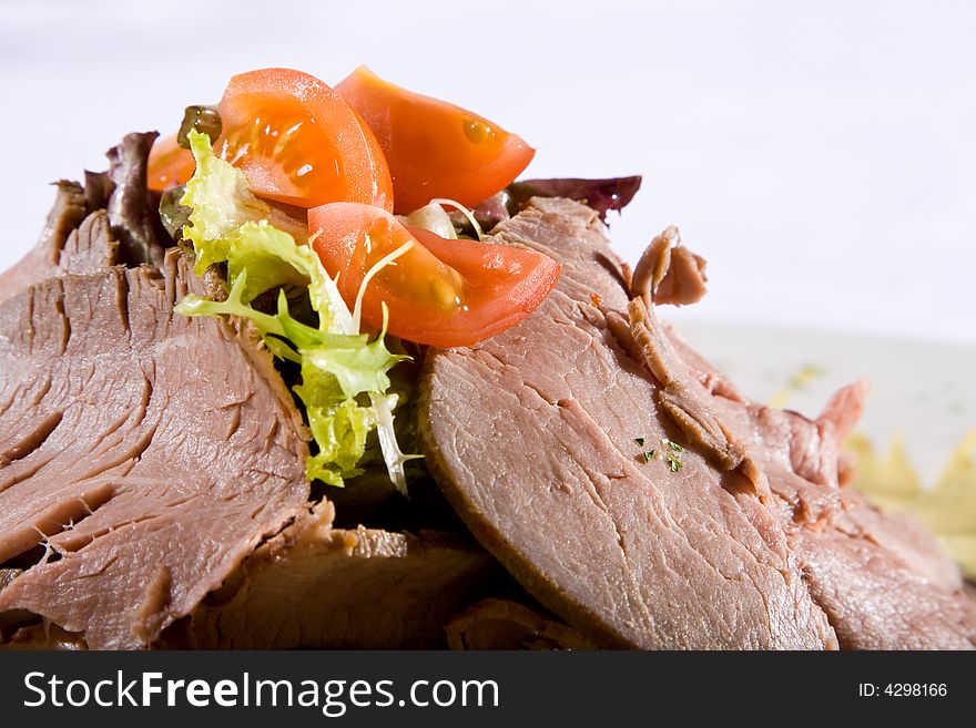 Beef meat with tomatoes and greens on a plate.