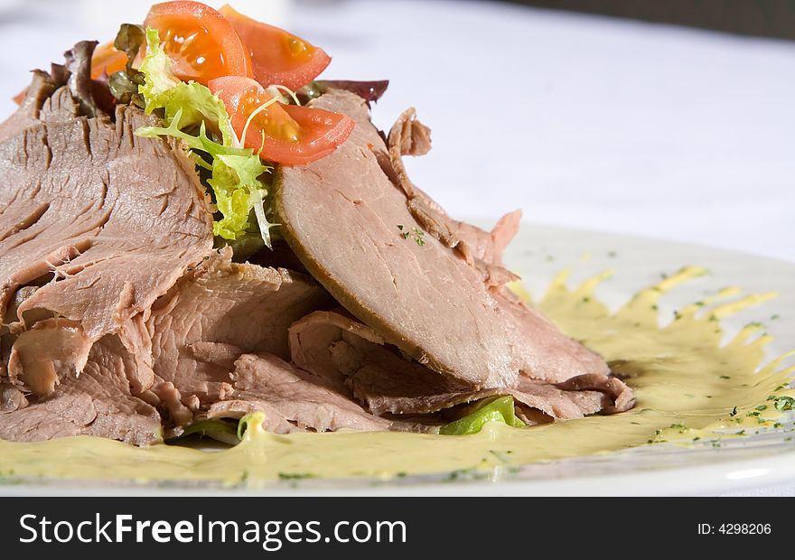 Beef meat with tomatoes and greens on a plate.