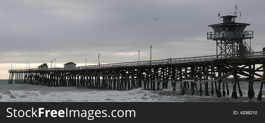 A couple walks on the pier in stormy weather.  Gulls fly by. A couple walks on the pier in stormy weather.  Gulls fly by.