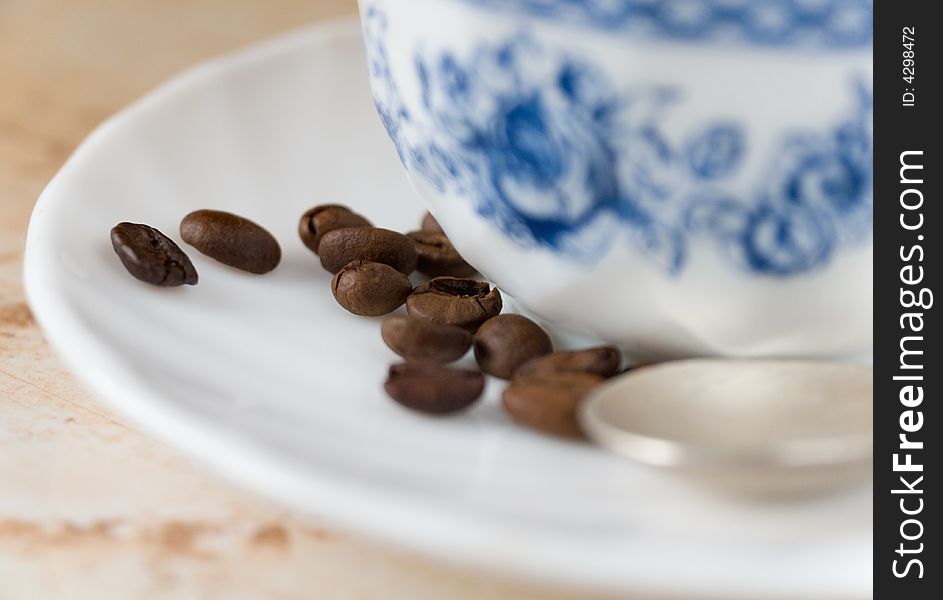 Some coffee beans on saucer with cup of coffee