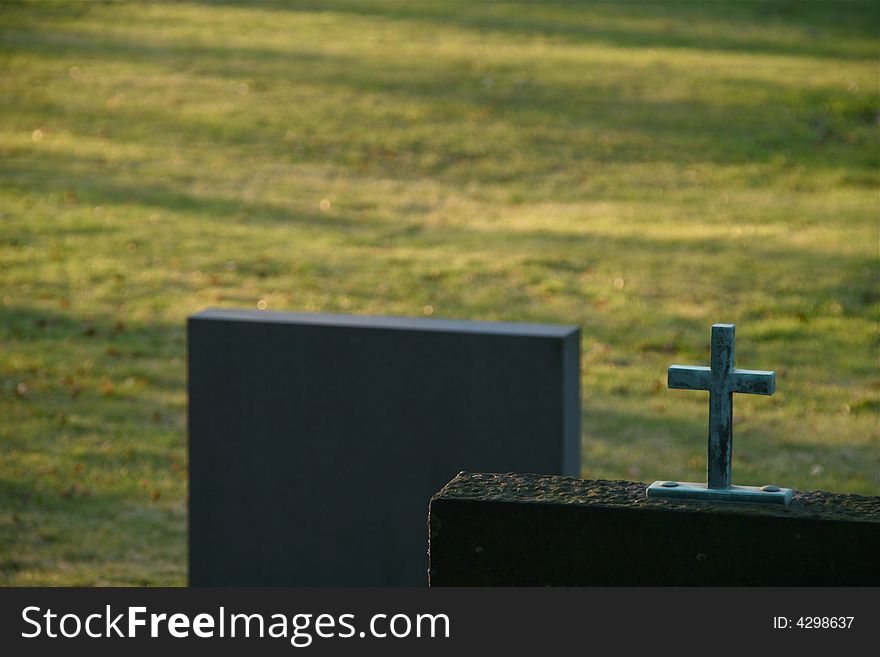 Two gravestone on a graveyard field. A cross. Two gravestone on a graveyard field. A cross