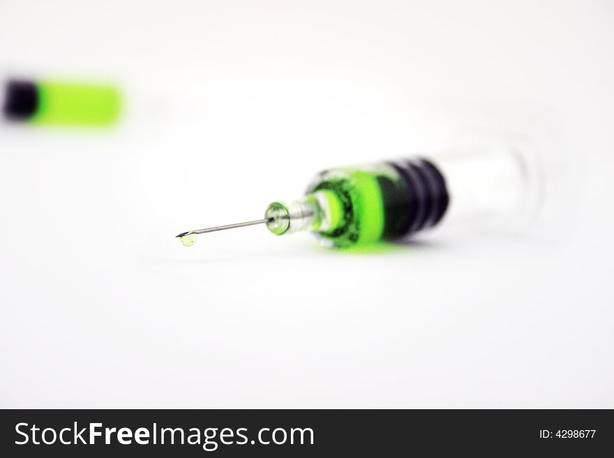 Syringe with green substance incide on white