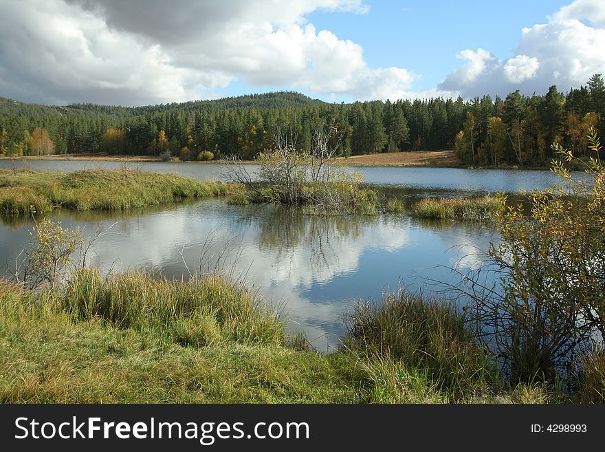 Autumn landscape. Lake in forest with reflection of clouds