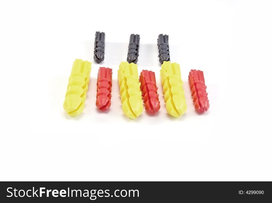 Three red,yellow and grey wall-plugs on a white background. Three red,yellow and grey wall-plugs on a white background