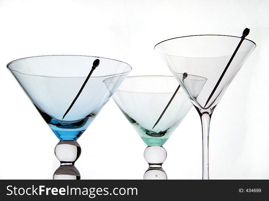 Three empty martini glasses with cocktail sticks and white background.