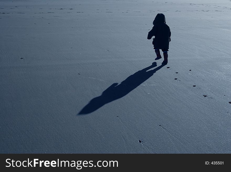 A young boy on a beach walking with purpose. A young boy on a beach walking with purpose.