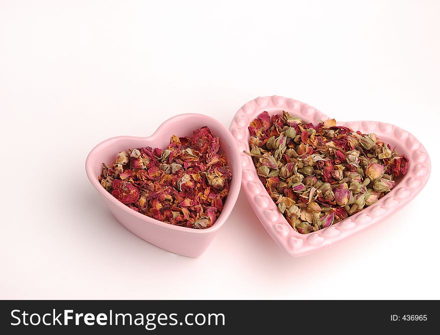 Two heart shaped dishes filled with rose petals. Two heart shaped dishes filled with rose petals