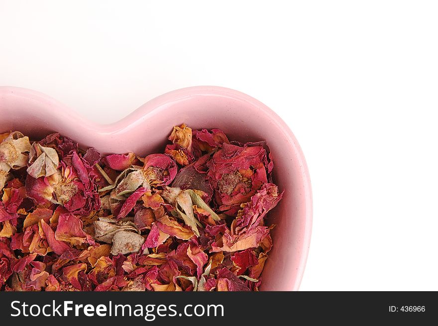 Rose petal potpourri in a pink heart shaped bowl. Rose petal potpourri in a pink heart shaped bowl